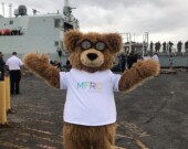 La mascotte du Centre de ressources pour les familles des militaires d’Esquimalt devant un bateau des Forces armées canadiennes | courtoisie   
