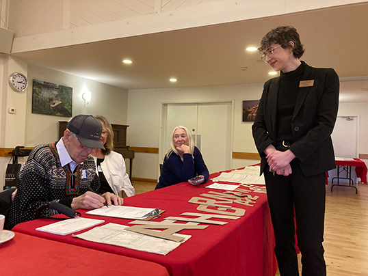 Kristian Frostad signs collection donation documents overseen by Jules Moses-Coats, Collections Manager, MMBC, with his spouse Darlene and daughter Vonda to his right. &mdash; Photo courtesy of Marian Toft