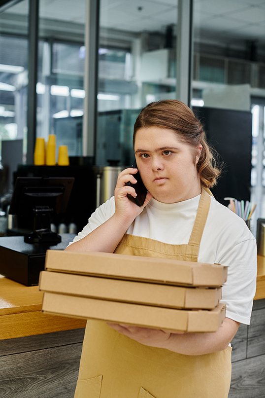 Young woman with Down Syndrome working in a cafe. | Photo by Lightfield Studios.  