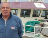 Herman Synnott pose devant le Enmali, bateau propriété de la communauté de Gesgapegiag basé à Rivière-au-Renard. Photo : Nelson Sergerie  