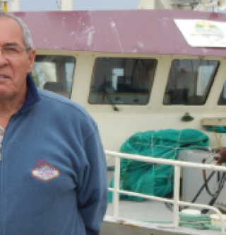 Herman Synnott pose devant le Enmali, bateau propriété de la communauté de Gesgapegiag basé à Rivière-au-Renard. Photo : Nelson Sergerie  