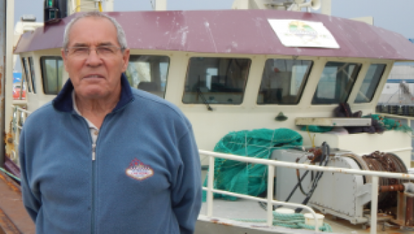 Herman Synnott pose devant le Enmali, bateau propriété de la communauté de Gesgapegiag basé à Rivière-au-Renard. Photo : Nelson Sergerie  